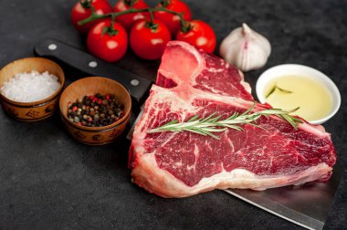 Taştan arka planda et bıçağındaki malzemelerle birlikte çiğ biftek yakın plan görüntüsü.