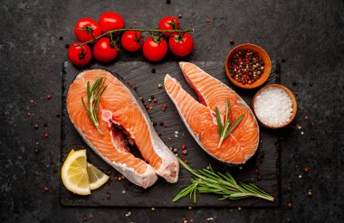 Çiğ balık somon bifteği ve taştan bir arka planda malzemeler.