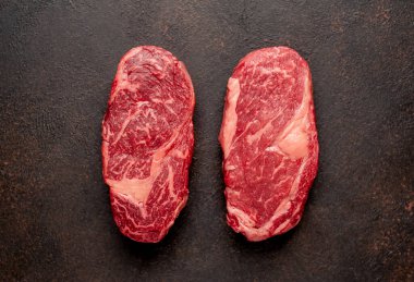 Arka planda baharatlı iki çiğ biftek.