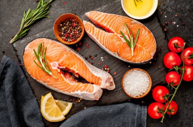 Çiğ balık somon bifteği ve taştan bir arka planda malzemeler.