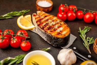 Izgara somon bifteği, arka planda et bıçağının üzerinde malzemeler var.