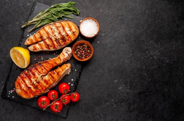 Izgara somon bifteği ve taştan bir arka planda malzemeler.