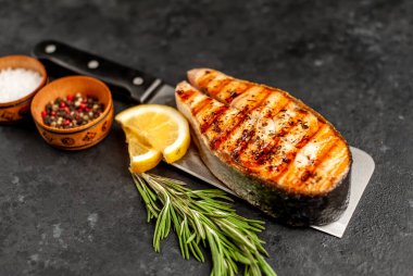 Izgara somon bifteği, arka planda et bıçağının üzerinde malzemeler var.