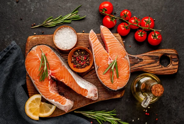 Çiğ balık somon bifteği ve taştan bir arka planda kesim tahtası malzemeleriyle yakın plan görüntüsü.