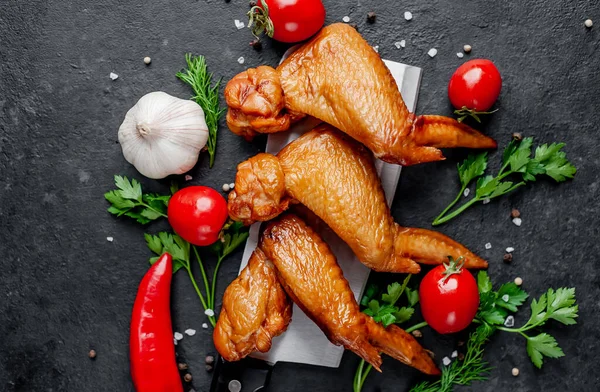 Et bıçağında tütsülenmiş kanatlar ve arka planda baharatlar.