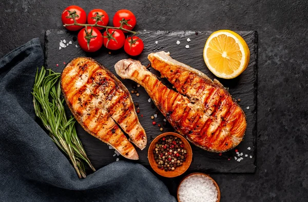 Izgara somon bifteği ve taştan bir arka planda malzemeler.