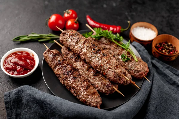 Lezzetli ızgara Lula kebapları şiş ve baharatlar arka planda.