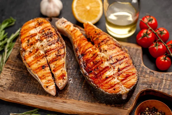 Izgara somon bifteği ve taştan bir arka planda kesim tahtası malzemeleriyle yakın plan görüntüsü.