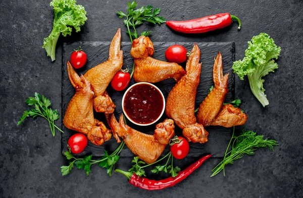 Smoked chicken wings with spices on a stone background