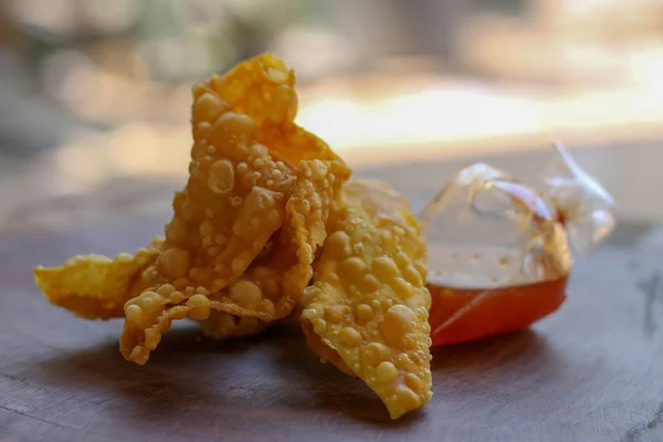 Bolinhos fritos, comida chinesa com molho em saco plástico em madeira — Fotografia de Stock