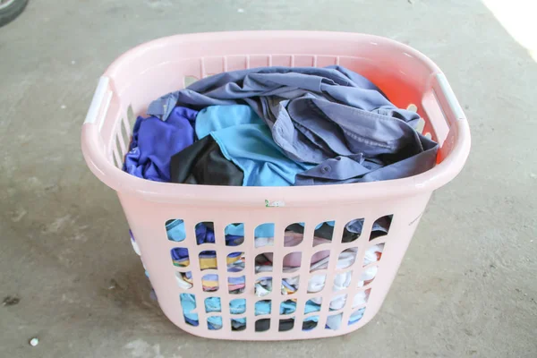 Pink Basket with dirty laundry on floor.