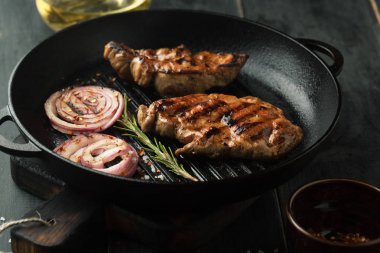 Baharatlar, biberiye ve karanlık bir adam üzerinde bir tavada biber biber soslu domuz eti, ızgara biftek