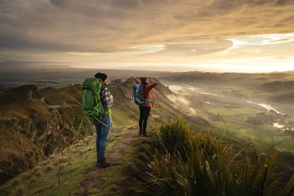 一对旅行的夫妇站在山顶上凝视着地平线 她张开了胳膊 旅行者和背包客概念 — 图库照片