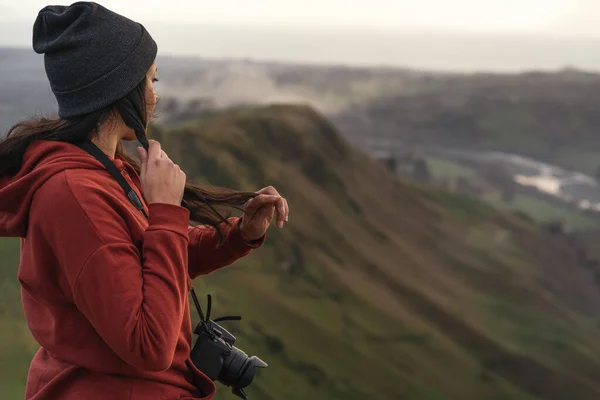 站在山顶时 一个女人拿着相机摸着她的头发 旅行概念 — 图库照片