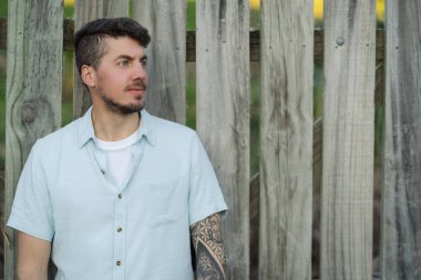 Ahşap arka planda profilde poz veren beyaz dövmeli adam. Uzay portresi fotoğrafçılığını kopyala.