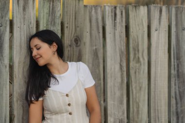 Esmer bir kadın profilde poz veriyor ve tahta arka planda gülümsüyor. Teklif alanı olan portre fotoğrafçılığı