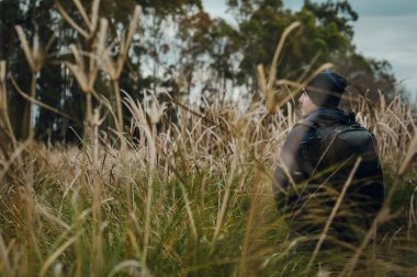 Genç adam koşuşturmaların ve çalıların ortasında yürüyor.