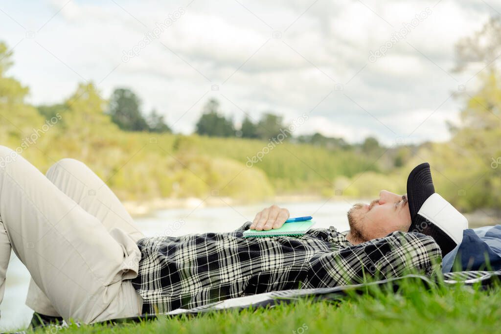 Caucasian man resting and relaxing on the grass and looking at the sky. Inspirational and relax concept