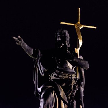 Gece büyük bir altın haç tutan bir köprü aziz heykeli