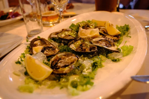 Plate of cooked oysters on a bed of salad