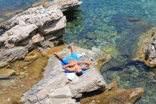 Man sunbathing on the stony beach on the Lapad Peninsula of Croatia