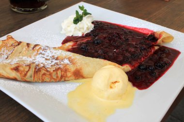 Vanilya dondurma reçel ve bir kare beyaz plaka üzerinde krema bir kepçe ile pancake