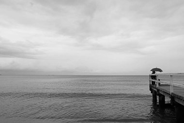 Sopot Polonya sahilinde gri bir gün ve iskelede bir şemsiye altında bir adam