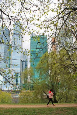 Kız parkta modern mimari kompleks Moskova şehir Rusya arka planda ağaçların arasında yürüyüş