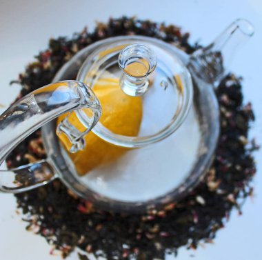 Beyaz bir masa üzerinde Cam şeffaf çaydanlık ve katkı maddeleri ile siyah çay etrafında dağınık