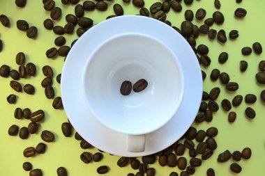 Temiz bir kahve fincanı, tabak ve kahve çekirdekleri masaya dağılmış natürmort