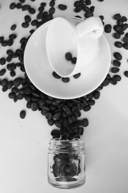 Temiz bir kahve fincanı, tabak ve kahve çekirdekleri masaya dağılmış natürmort