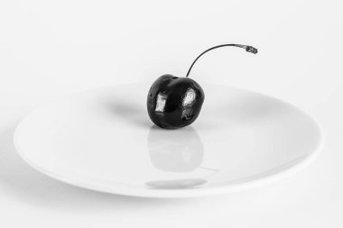 Beyaz bir arka plan üzerinde beyaz bir tabak yakın çekim bordo kiraz berry