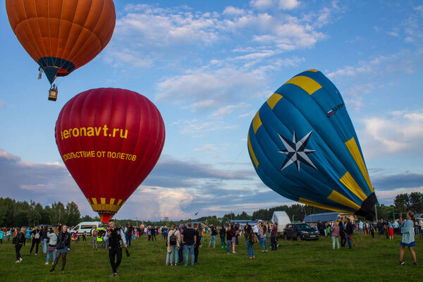 Pereslavl-Zalessky, Yaroslavl region / Russia - July, 20, 2019: Warming up at the start of balloons and take-off with passengers in a basket at the Aeronautics Festival on a summer evening in front of a large audience