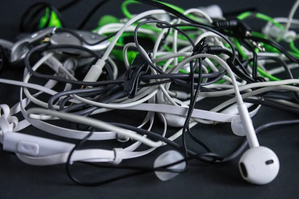 A bunch of mixed-wire headphones close-up on a gray background