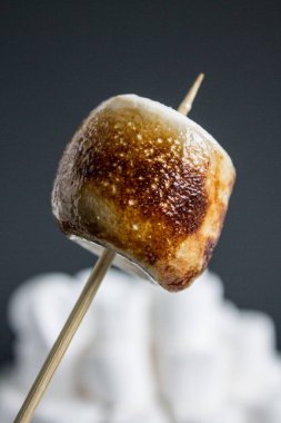 White marshmallow on a stick burnt by fire caramelized clipart