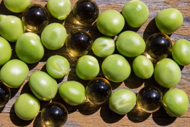 Ahşap arka planda yeşil bezelye ve omega-3 kapsülleri