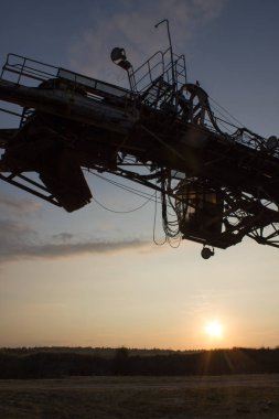 Gün batımına karşı ışığa karşı çok kovalı bir ekskavatör devinin parçası