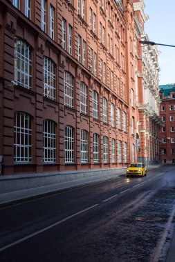 Moskova / Rusya-Eylül 14, 2019: Kırmızı tuğla evler ve ıslak asfalt üzerinde sarı taksi ile tarihi sokak
