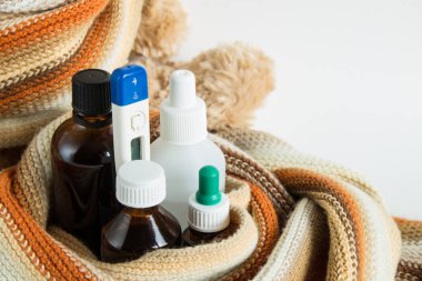 Sıcak bir atkı sarılı ilaç ve termometre