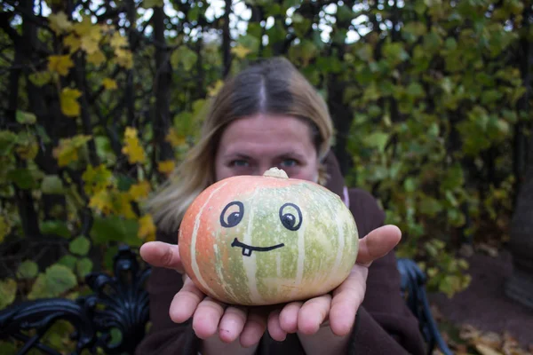 Kvinna Och Pumpa Händerna Med Ett Lustigt Ansikte Ritat — Stockfoto