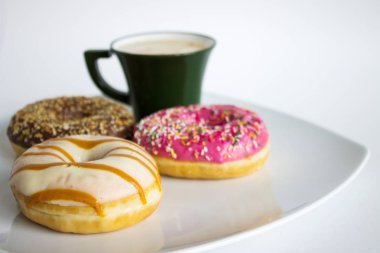 Beyaz tabakta taze renkli çörekler ve bir fincan kahve.