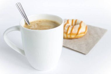 Büyük beyaz kapuçino bardağı ve kremalı donut.