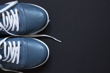 Gri-mavi kadın deri ayakkabıları, beyaz bağcıklı siyah arka plan ve fotokopi alanı.