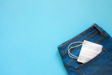 Kotun arka cebindeki tıbbi tek kullanımlık maske mavi arka plan ve kopyalamak için yer kaplıyor. Kavram: Koronavirüs salgını sırasında koruma