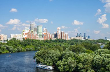 Moskova 'daki modern yerleşim binalarının panoramik manzarası. Güneşli bir yaz günü. Yeşil ağaçlar ve Moskova nehri ile tekne ve kopyalama alanı.