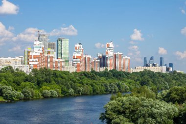Moskova 'daki modern yerleşim binalarının panoramik manzarası. Güneşli bir yaz günü. Yeşil ağaçlar ve Moskova nehri ile tekne ve kopyalama alanı.