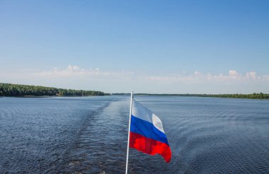 Rus bayrağı, su nehrinin arka planında ve açık mavi gökyüzünde ve kopyalamak için uzayda kapanıyor