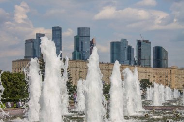Çeşme fıskiyeleri Moskova 'nın modern binalarına yakın çekim yapıyor ve bir yaz günü gökyüzü bulutlu ve kopyalamak için alan yaratıyor.