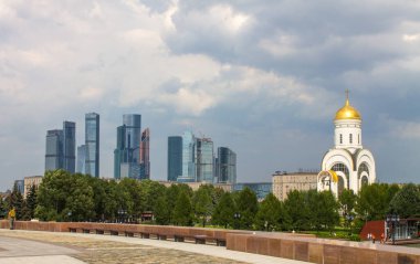 Zafer Parkı 'ndaki Poklonnaya tepesindeki Aziz George Kilisesi ve Moskova şehrinin modern binalarının manzarası.