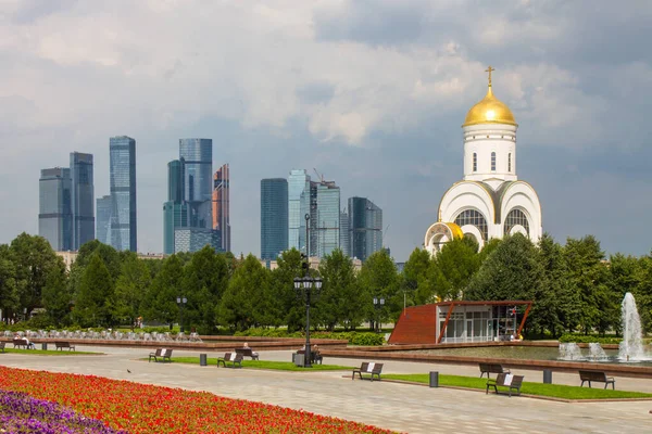Zafer Parkı 'ndaki Poklonnaya tepesindeki Aziz George Kilisesi ve Moskova şehrinin modern binalarının manzarası.
